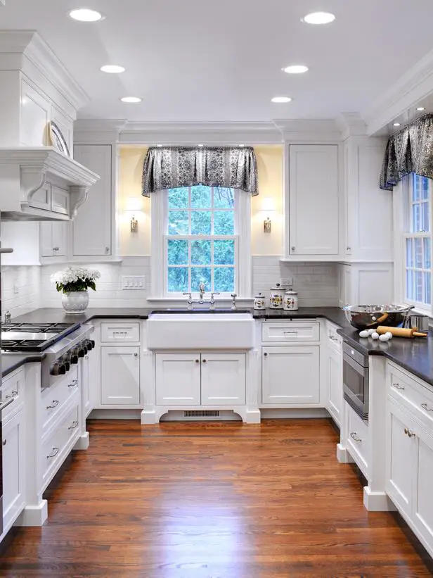 This Grey and white country farmhouse kitchen has both a warm rustic feel to it and modern lines and appearance.  The dark counter tops accent the white cabinets and brick backsplash perfectly. The wood floors tie it all together. Just beautiful!