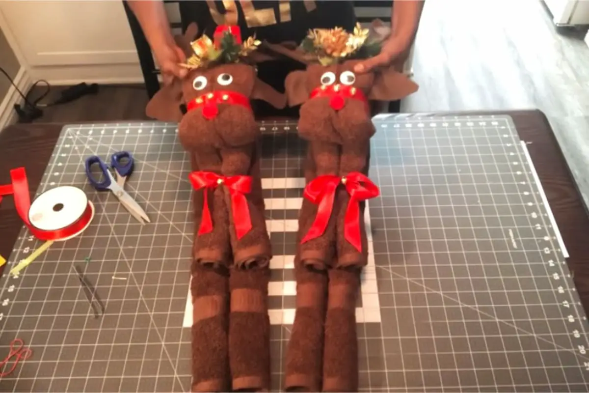 towel reindeer craft tutorial step 6 - after folding your brown bath towel into the shape of a reindeer, it's time to decorate with riboons, bows, jiggly ees, antlers and more. What a fun and easy reindeer craft for adults to make